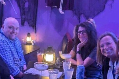 Group of five people at a dimly lit table in a Halloween-themed setting.