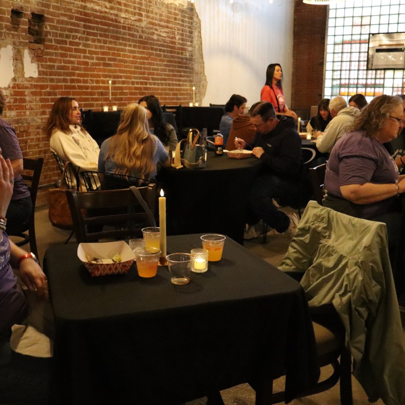 People sitting at tables in a dimly lit rustic brick-walled venue.