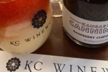 Drink and jar on table with 'KC Wine' and 'Raspberry Chipotle' labels.
