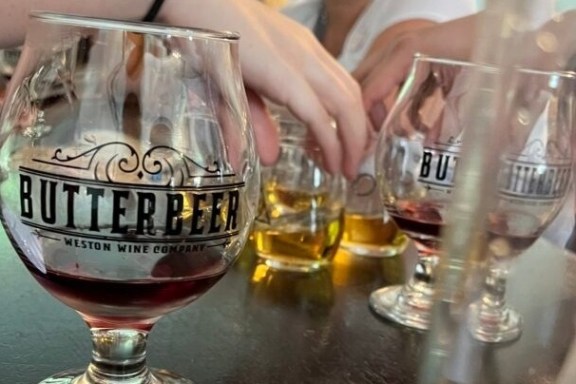 Butterbeer glasses on a table with people reaching for them.
