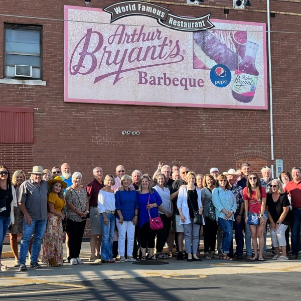 Group of people posing in front of Arthur Bryant's Barbeque restaurant in sunlight.